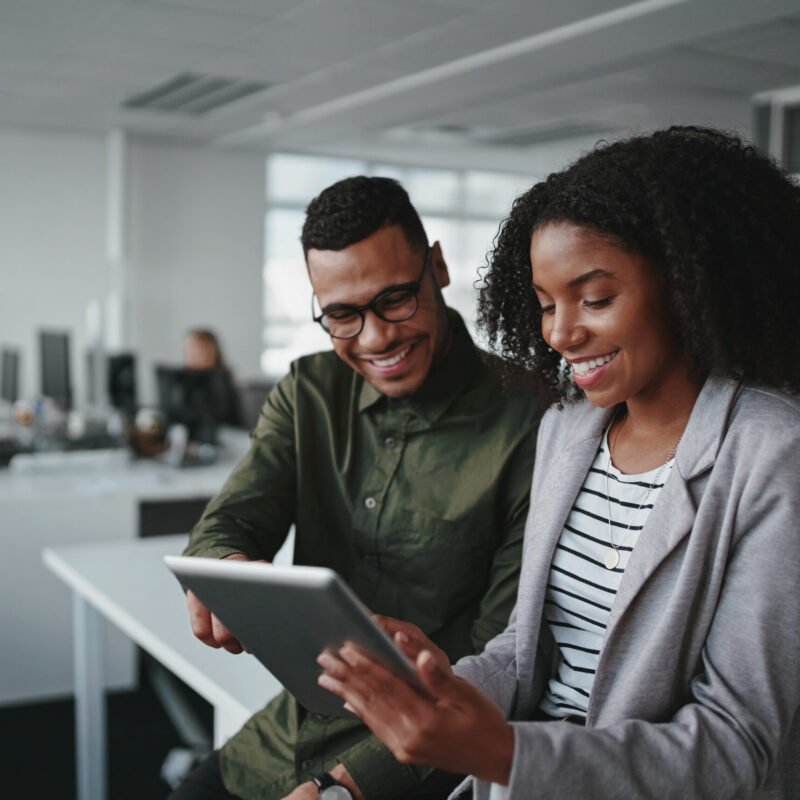 Smiling young african american professional businessman and businesswoman together working online with a digital tablet in office Professional young businesspeople using tablet computer smiling in office